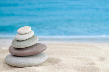 Fototapeta na wymiar Balance stones pebbles stack pyramid for relaxation meditation with sea or ocean waves on background for horizontal wallpaper