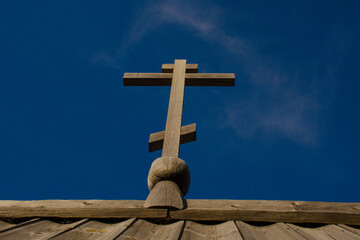 Wooden Orthodox cross against the background of a clear blue sky.