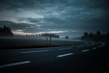 Naklejka na ściany i meble Empty morning road through foggy landscape