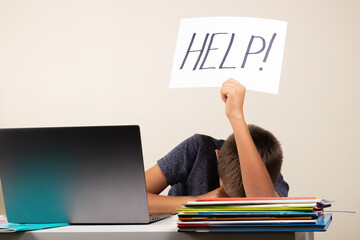 Learning difficulties, school, education, online remote learning concept. Sad kid with laptop computer holding card with Help word - obrazy, fototapety, plakaty