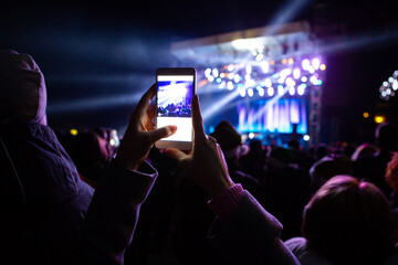 A girl is taking pictures of a street concert on the phone	
