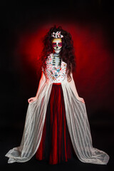 Fototapeta premium Girl dressed as a witch on Halloween ta dark red background