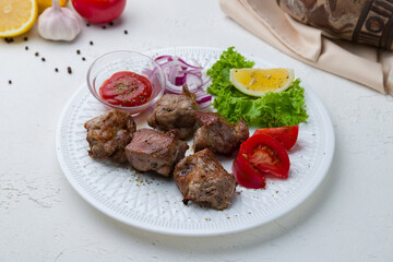skewers of mutton flesh with sause and vegetables on white concrete table