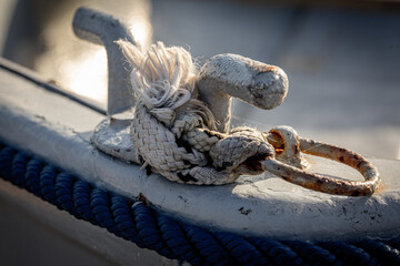 A close up of boat ropes tied up around the cleat of a wooden boat using selective focus