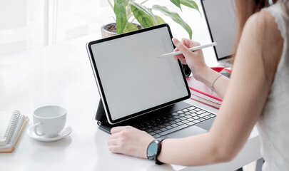 Closeup view of female hands holding digital pen writing on tablet screen while sitting at the...