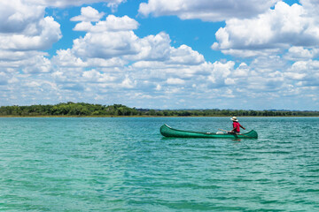 Fisherman in canoe boat in lake Itza with sunny cloud sky, El Remate, Peten, Guatemala