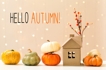 Hello autumn message with collection of autumn pumpkins with a toy house