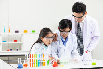 science teacher doing or testing a chemical experiment with child students in laboratory classroom
