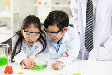 child students doing or testing a chemical experiment with science teacher by them side in laboratory classroom