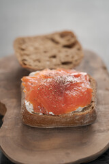 rye ciabatta sandwich with smoked salmon and cream cheese on olive board