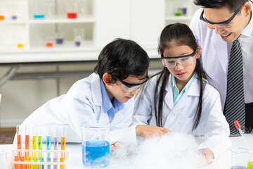 child students doing or testing a chemical experiment with science teacher by them side in laboratory classroom