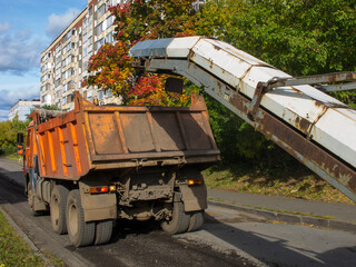 Loading on a dump truck of old asphalt chips during road repair. © miraleks