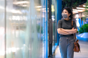 new normal after covid epidemic  young business asian female wear facial protection mask walking in center square department store mall new lifestyle after spread of corona virus covid-19