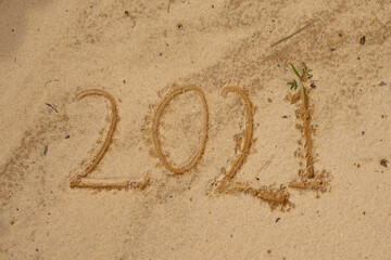 Photo of wave washing out 2021 numbers written on wet sand at beach. Concept of New Year, Christmas and travel on winter holidays.