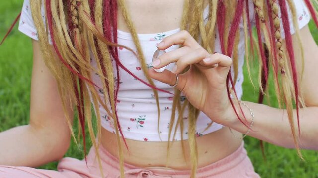 Outdoors portrait of a girl with dreadlocks hairstyle holding in hand little natural stone rock crystal, rhinestone
