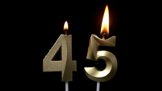 Burning golden birthday candles on black background, number 45	