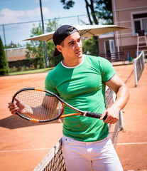 Portrait of young athletic man on tennis court.