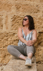 portrait of caucasian woman sitting on stone wall