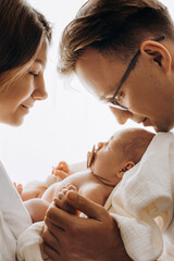 Beautiful parents with newborn baby, loving mom hold little daughter in arms, caring dad gently...