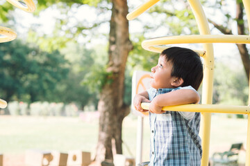 Obraz premium Asian little boy holding the curve frame on the playground and looking up high.