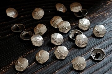 Metal buttons on the wooden surface of the table. Stylish sewing accessories.