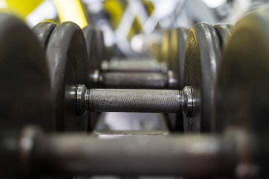 Close up on row of dumbbells in the rack in gym - selective focus background - dark image strength and fitness concept
