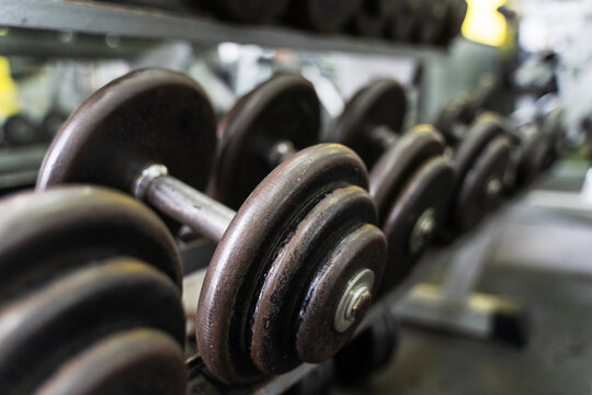 Close up on row of dumbbells in the rack in gym - selective focus background - dark image strength and fitness concept