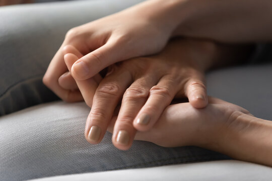 Forgive me, mommy. Hands of young female or teenage girl tender covering and caressing palm of middle aged old woman mother or grandma apologizing or asking for advice during sincere talk, close up