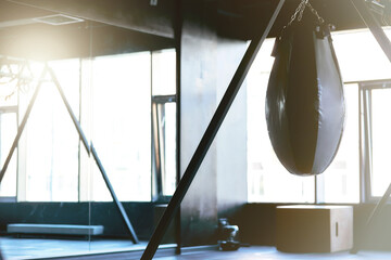Fototapeta na wymiar Boxing. Black punching bag in empty gym, selective focus