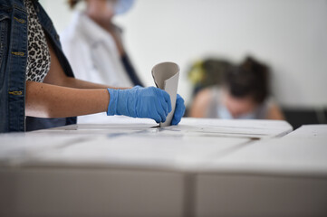 Unrecognizable person casting a vote into the ballot box during corona virus pandemic