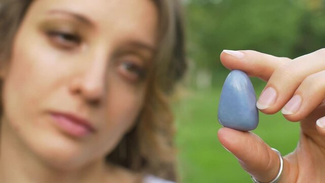 Outdoors portrait of a girl with dreadlocks hairstyle holding in hand little natural stone blue angelite