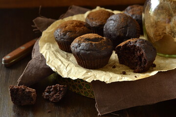 Chocolate banana muffin sprinkled with cocoa on dark background