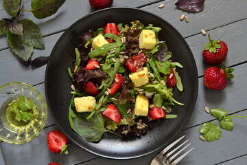 Leaf salad with strawberries, cheese and seeds, top view