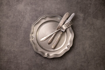 vintage cutlery on a pewter plate. Concrete background. Fork, knife, spoon