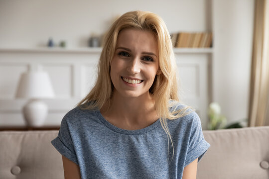 Portrait of smiling young female posing at home looking at camera while making videocall, recording vlog, passing distant job interview, providing internet consultation using webcam, profile picture