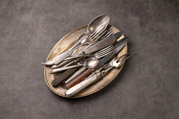 vintage cutlery on a copper plate. Concrete background. Fork, knife, spoon