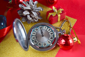 Christmas alarm clock on red and gold colored wrapping paper, eve time concept, top view, fairy tale magic effect
