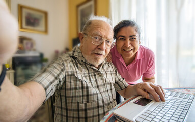 Elderly man with her caregiver taking a selfie photo at home