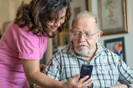 Smiling senior man and caregiver with smartphone are doing a videocall