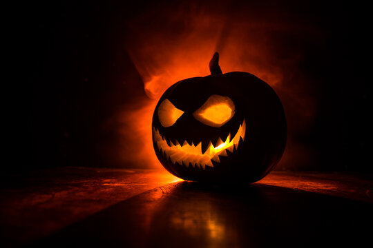 Halloween pumpkin smile and scary eyes for party night. Close up view of scary Halloween pumpkin with eyes glowing inside at black background