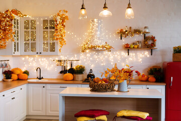 Autumn kitchen interior. Red and yellow leaves and flowers in the vase and pumpkin on light...