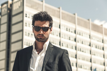 Handsome businessman with sunglasses, outdoor in the city. Charming and modern style, with shirt...