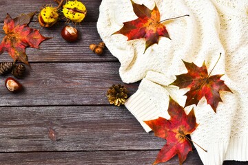 Obraz premium White warm sweater and autumn leaves on a wooden background. Flat lay, top view of autumn decoration. copy space. 