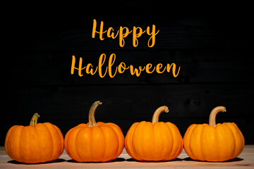 Yellow pumpkin on wooden black background with text. Halloween concept.