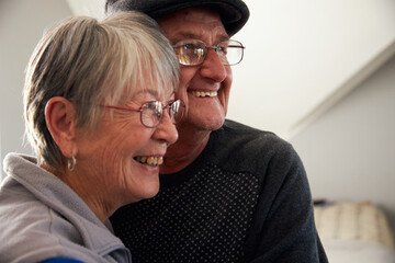 Loving Senior Couple Laughing And Smiling As They Hug Each Other At Home Together