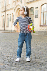 Escape with penny skateboard. Little skater listen to music in headphones. Small kid hold penny...