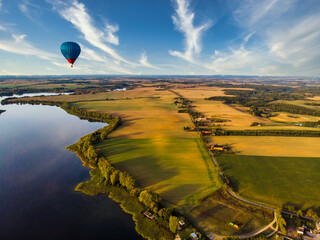Heissluftballon am Abend über Feldern und einem See