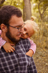 The baby hugs dad. Father holds a cute little girl in his arms. Autumn portrait of a child. Happy family and childhood moments.