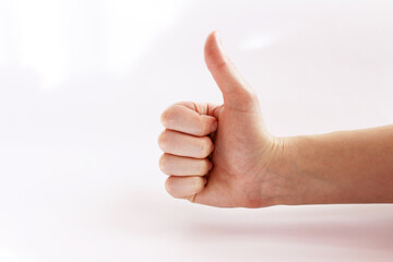 Woman hand close-up on a white background. Thumbs up.