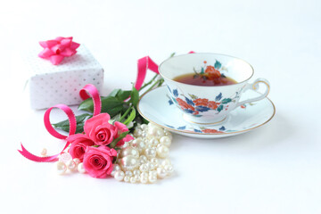 ホットピンクのバラの花束とパールと贈り物と紅茶